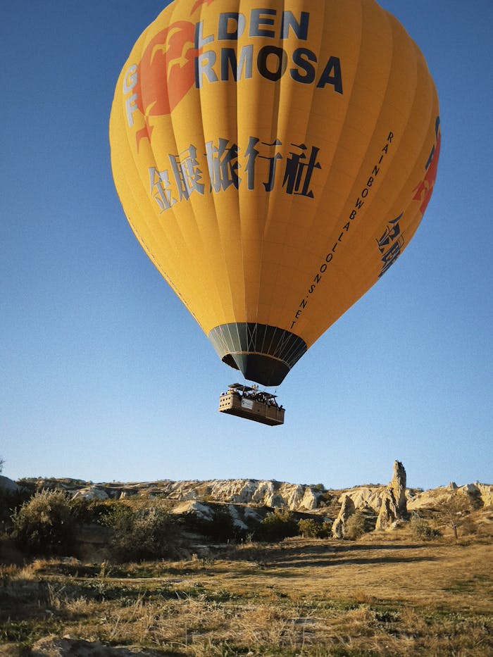 Hot air balloon flying over Cappadocias unique landscape during sunrise.